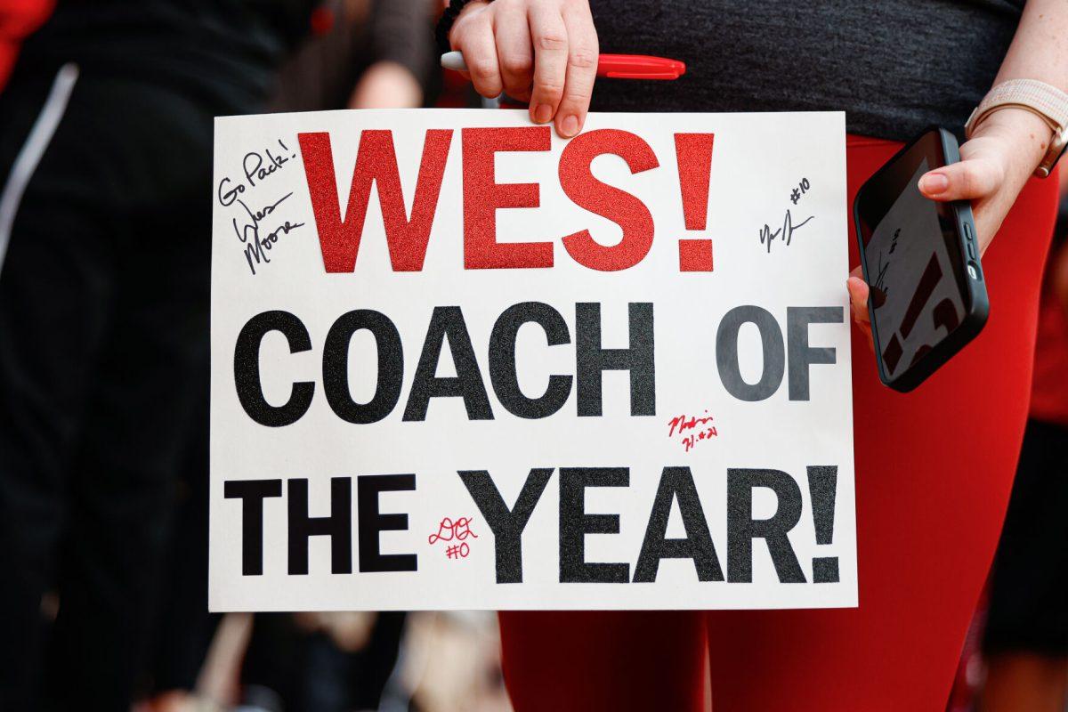 A fan holds up a "Coach of the Year" sign for the head coach Wes Moore during the team's welcome back to Reynolds Coliseum on Saturday, March 29, 2025. Moore is a Naismith Coach of the Year semifinalist.