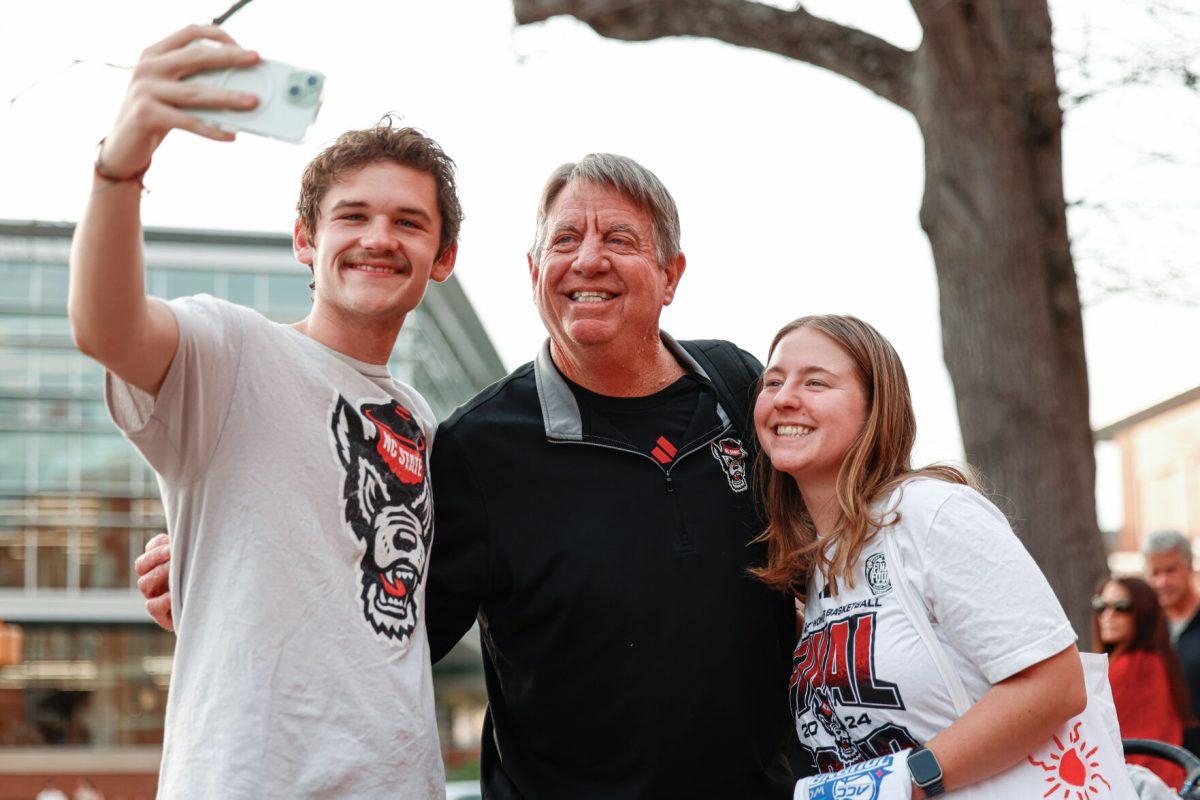 Women's basketball head coach Wes Moore takes a selfie with a couple of fans during the team's welcome back to Reynolds Coliseum on Saturday, March 29, 2025.