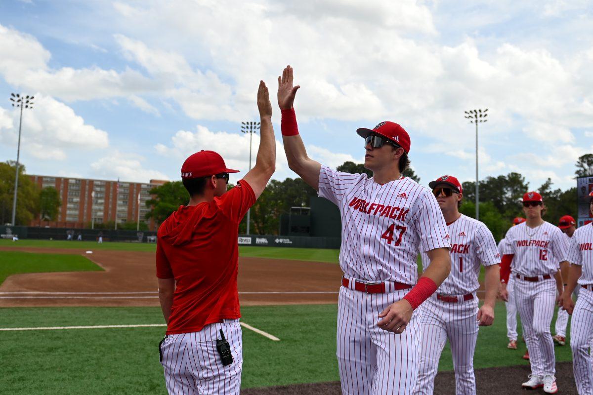 Sophomore outfielder Jake Bechtel high fives his assistant coach before the game against Virginia on April 5, 2025 at Doak Field at Dail Park. NC State bested Virginia 9-2.
