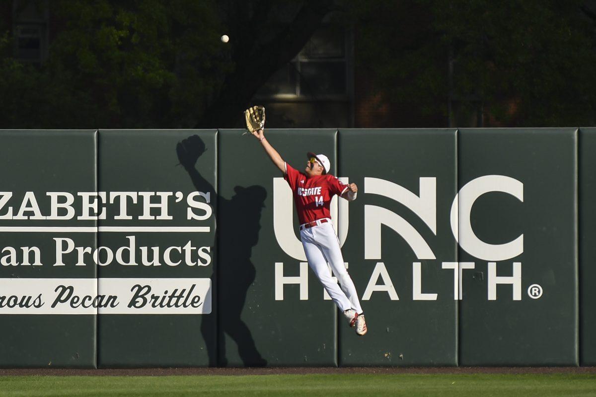 Freshman outfielder Ty Head leaps and catches a ball at the wall during the Wolfpack's home game against the Virginia Cavaliers on Doak Field at Dail Park on Friday, April 4, 2025. Head stole a home run on defense and went two for two before being walked the rest of the game from the batter's box. The Cavaliers beat the Wolfpack 8-6 to take the first game of the series.