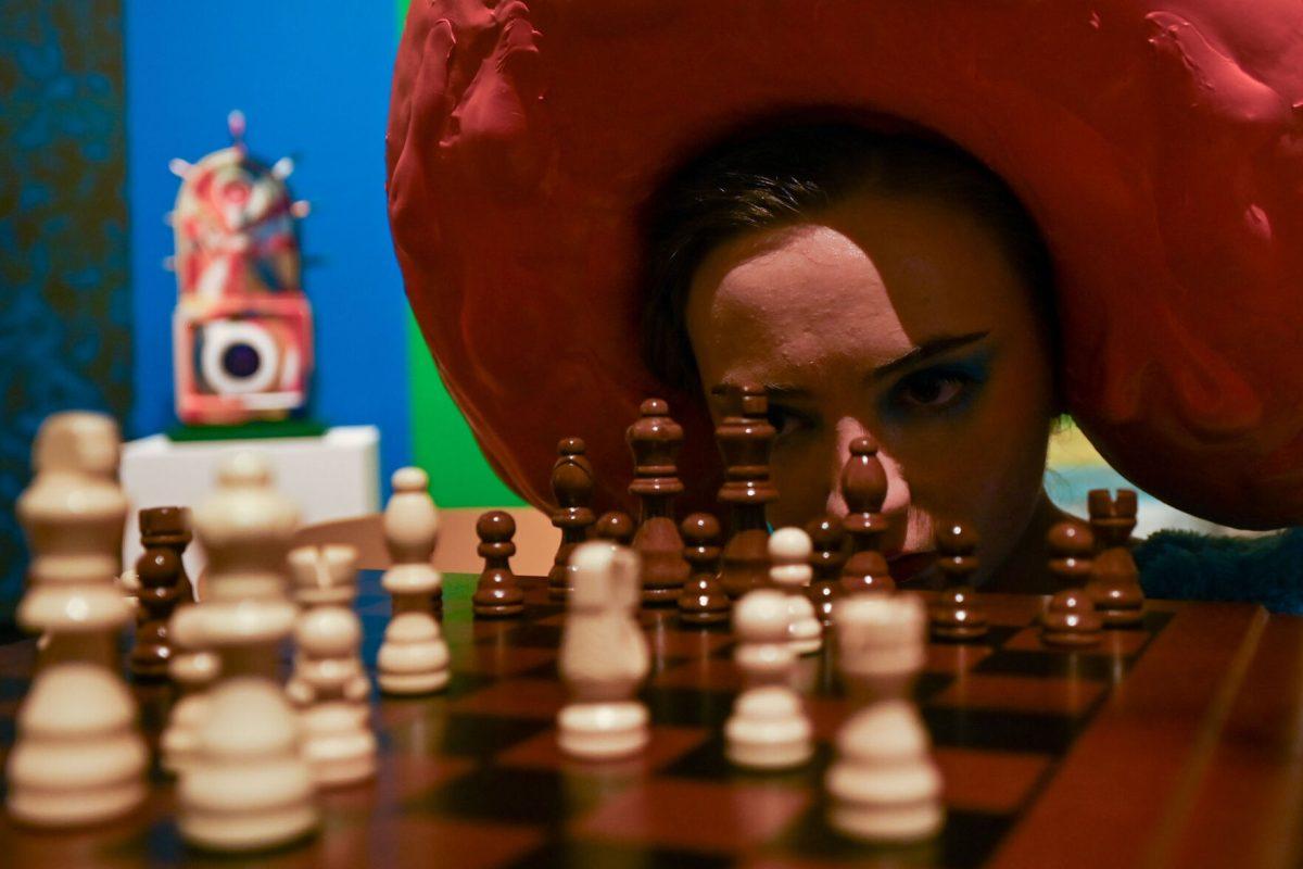 Savanah Buck, a fourth-year studying biochemistry, stares through chess pieces while performing Caleb Sowah and Maia Lindgren's piece titled Life After Death during Art2Wear: Revive at the Gregg Museum of Art &amp; Design on Thursday, April 24, 2025. Audience members were urged to interact with this piece, and to play chess with the individuals wearing the art.