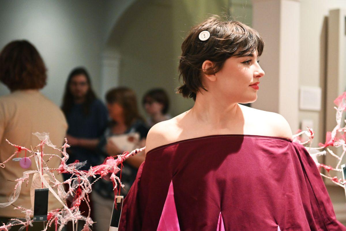 Sophie Dickerson, a fourth-year studying graphic and experience design, models her piece &#8220;Ornaments of Being&#8221; during the Art2Wear: Revive! show at the Gregg Museum of Art and Design on Thursday, April 24, 2025. Dickerson&#8217;s piece uses neuron branches decorated with childhood photos and memorabilia to revive memories of her past.