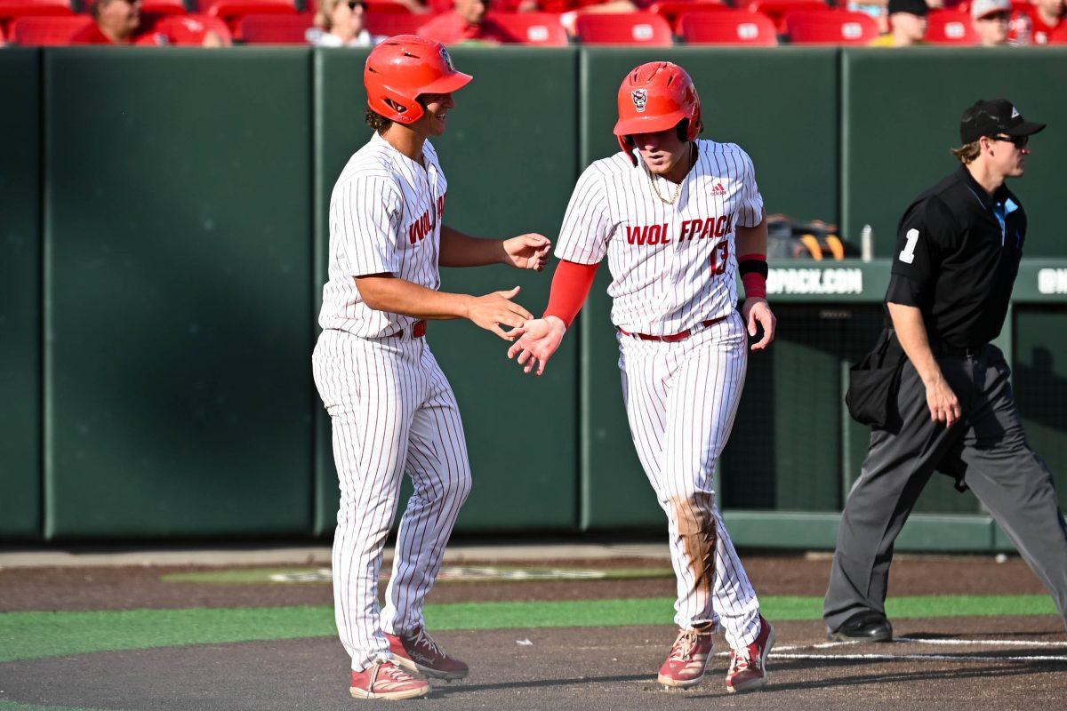 Sophomore catcher Alex Sosa high fives sophomore infielder Chris McHugh after scoring two runs during the game against Virginia at Doak Field at Dail Park on Saturday, April 5, 2025. The Wolfpack beat the Cavaliers 9-2.