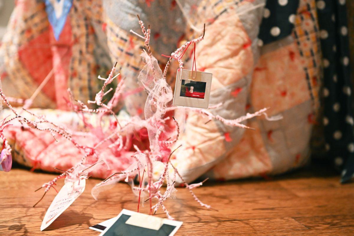 A photo hangs from part of the piece, &#8220;Ornaments of Being&#8221; by Sophie Dickerson, a fourth-year studying graphic and experience design, during the Art2Wear: Revive! show at the Gregg Museum of Art and Design. Dickerson&#8217;s piece uses neuron &#8220;branches&#8221; decorated with childhood photos and memorabilia to revive memories of her past.
