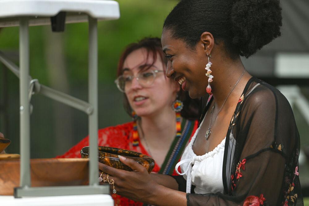 K Brinson, a third-year PhD student studying plant biology, and Erin Logan, a first-year PhD student studying plant biology, admire wooden bowls at a vendor's stall during NC State's 35th Annual Powwow at Miller Fields on Saturday, April 5, 2025. The event, sponsored by the Multicultural Student Association, featured various stalls for Native businesses selling hand-crafted jewelry, bowls, flags and more.