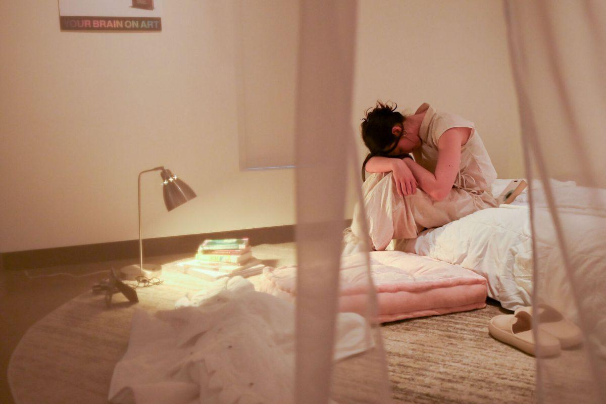 AK Stipanov, a fourth-year studying environmental design in architecture, rests her head while performing Elle Newkirk's Palingenesis during Art2Wear: Revive at the Gregg Museum of Art &amp; Design on Thursday, April 24, 2025. Instead of a traditional fashion runway, Art2Wear displayed the wearable artwork through performance art done by the artists and models.