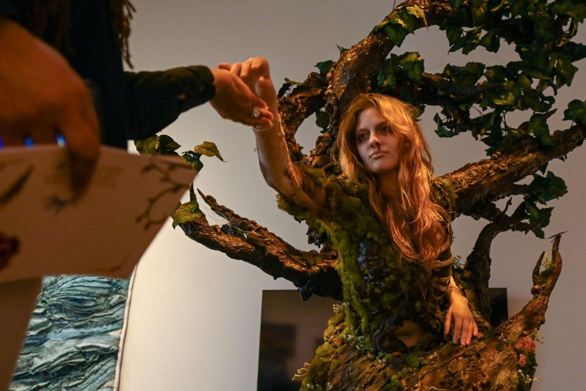 Bailey Lawson, a second-year in graphic design, hands an audience member an acorn while performing Mia Danford-Klein's piece called The Return Home during Art2Wear: Revive at the Gregg Museum of Art &amp; Design on Thursday, April 25, 2025. Art2Wear is an educational event where students are able to produce wearable art, students work in a studio time throughout the year to produce artwork to be shown during the show.