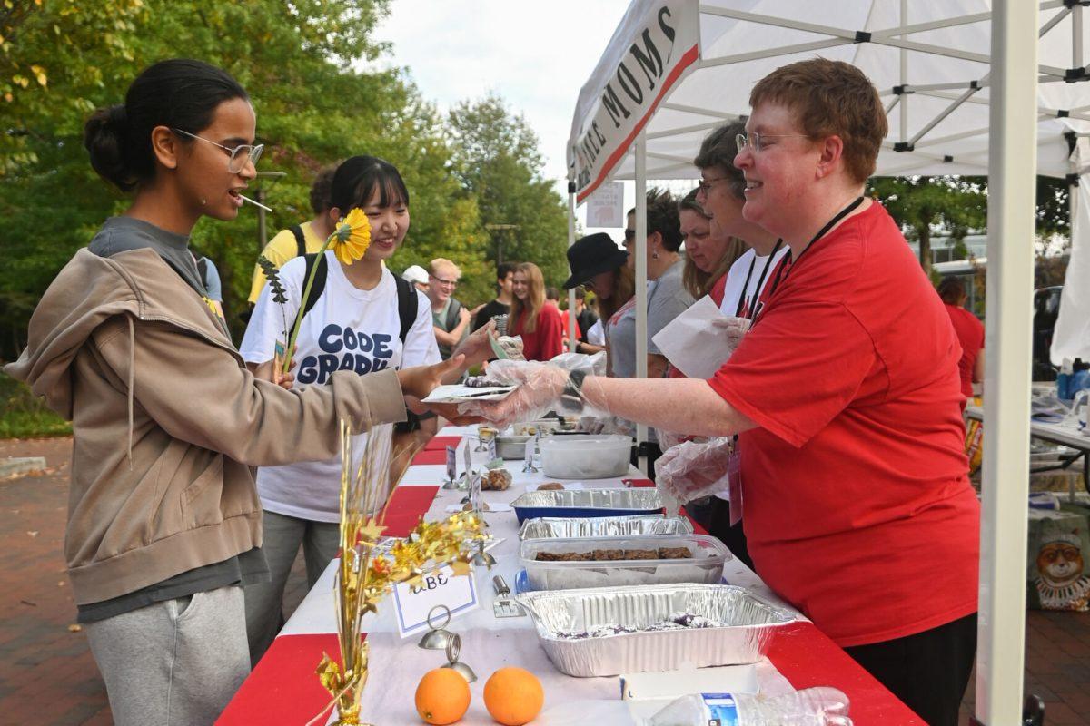 Moms chat as they hand students baked goods during Free Moms on Wolf Plaza on Thursday, Nov. 7, 2024. According to their website, Free Moms' mission is to create a haven of unconditional love and acceptance for the students of NC State University. Through our weekly gatherings, we provide a physical space where every student is embraced, celebrated and supported.