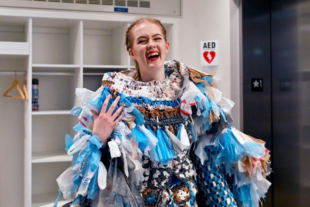 Meghan Mersch, a 2024 graduate of the graphic and experience design program, smiles before performing her piece &#8220;Baggage&#8221; during the Art2Wear: Revive! show at the Gregg Museum of Art and Design on Thursday, April 24, 2025. Mersch&#8217;s design aims to shed light on overconsumption and waste, and it is made entirely out of plastic grocery bags.