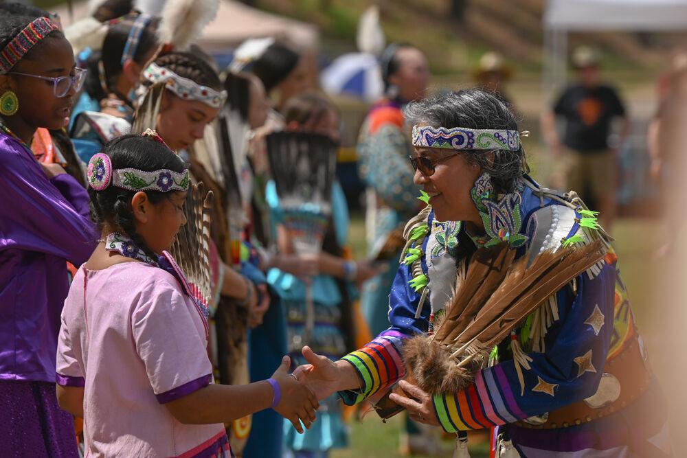 A young dancer shakes hands with a judge after performing during NC State's 35th Annual Powwow at Miller Fields on Saturday, April 5, 2025. The event included displays of various Indigenous dance styles by people of all ages.