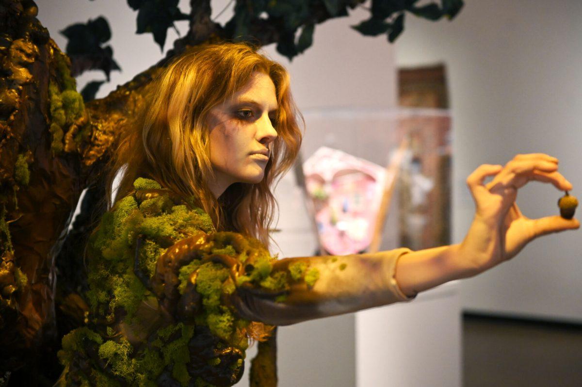 Bailey Lawson, a second-year studying graphic and experience design, hands an audience member an acorn while modeling &#8220;The Return Home&#8221; by Mia Danford-Klein during the Art2Wear: Revive! show at the Gregg Museum of Art and Design on Thursday, April 24, 2025. &#8220;The Return Home&#8221; is a tribute to the cycle of life, death, and rebirth, and explores the balance between life&#8217;s fragility and strength using elements of nature.