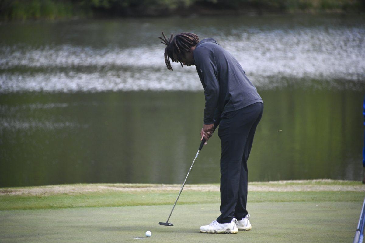 Freshman Adam Pederson taps the golf ball into the hole during the Stitch Intercollegiate golf match on Lonnie Poole Golf Course on Friday, April 12, 2024. Pederson finished the first round with 73 points.