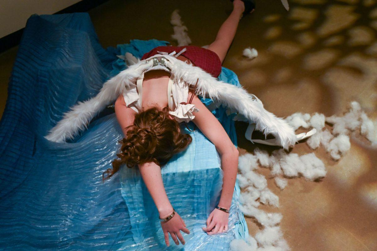 Lauren Nance, a second-year studying fashion and textile management, lies at the end of Mia Potter and Devyn Williams' piece from The Fall of Icarus during Art2Wear: Revive at the Gregg Museum of Art &amp; Design on Thursday, April 25, 2025. Instead of a traditional fashion runway, Art2Wear displayed the wearable artwork through performance art done by the artists and models.