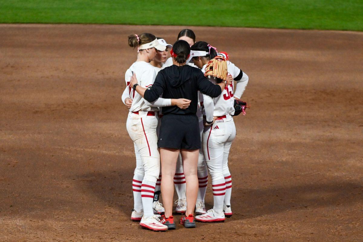 Assistant coach Grayson Radcliffe (center) speaks to members of the softball team during the game against Virginia Tech at Dail Softball Stadium on Friday, April 5, 2025. The Wolfpack lost to the Hokies 10-2.