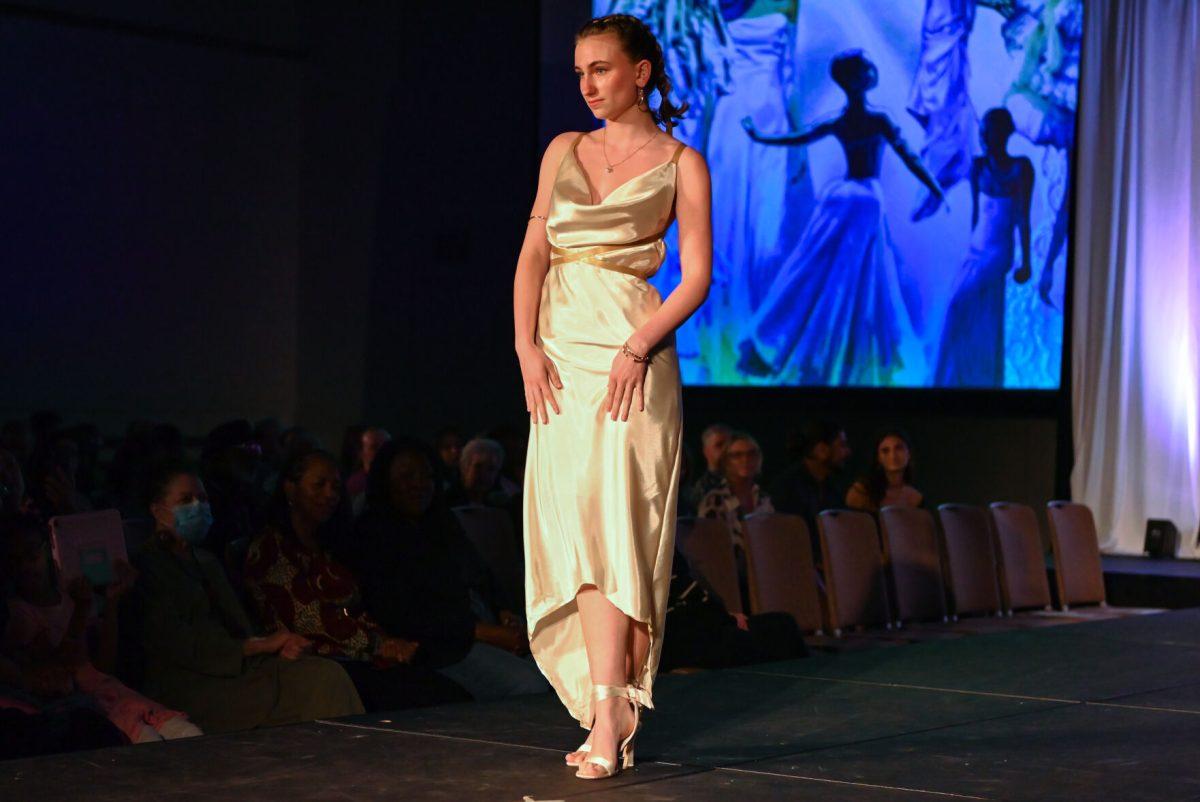 A model crosses her feet in a pose wearing a dress from the collection "Prima," designed by Sophia Stacy, a second-year studying fashion design, during the 27th Annual Fashion Expose at Talley Student Union on Thursday, April 10, 2025. Hosted by the NC State Wilson College of Textiles African American Textile Society, the event highlighted the hard work of students.
