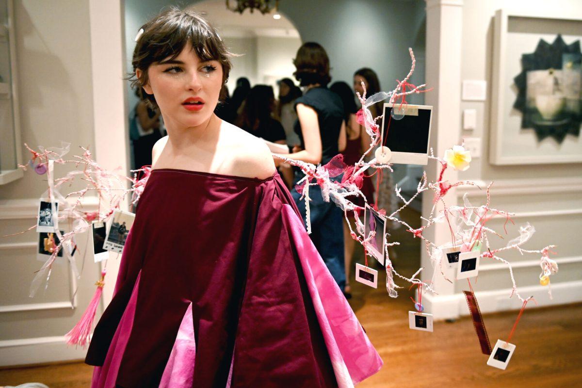 Sophie Dickerson, a fourth-year studying graphic and experience design, performs her piece &#8220;Ornaments of Being&#8221; during the Art2Wear: Revive! show at the Gregg Museum of Art and Design on Thursday, April 24, 2025. Dickerson&#8217;s piece uses neuron branches decorated with childhood photos and memorabilia to revive memories of her past.