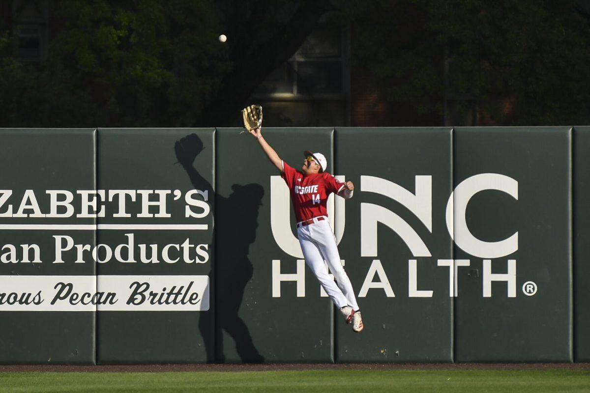 Freshman outfielder Ty Head leaps and catches a ball at the wall during the Wolfpack's home game against the Virginia Cavaliers on Doak Field at Dail Park on Friday, April 4, 2025. Head stole a home run on defense and went two for two before being walked the rest of the game from the batter's box. The Cavaliers beat the Wolfpack 8-6 to take the first game of the series.