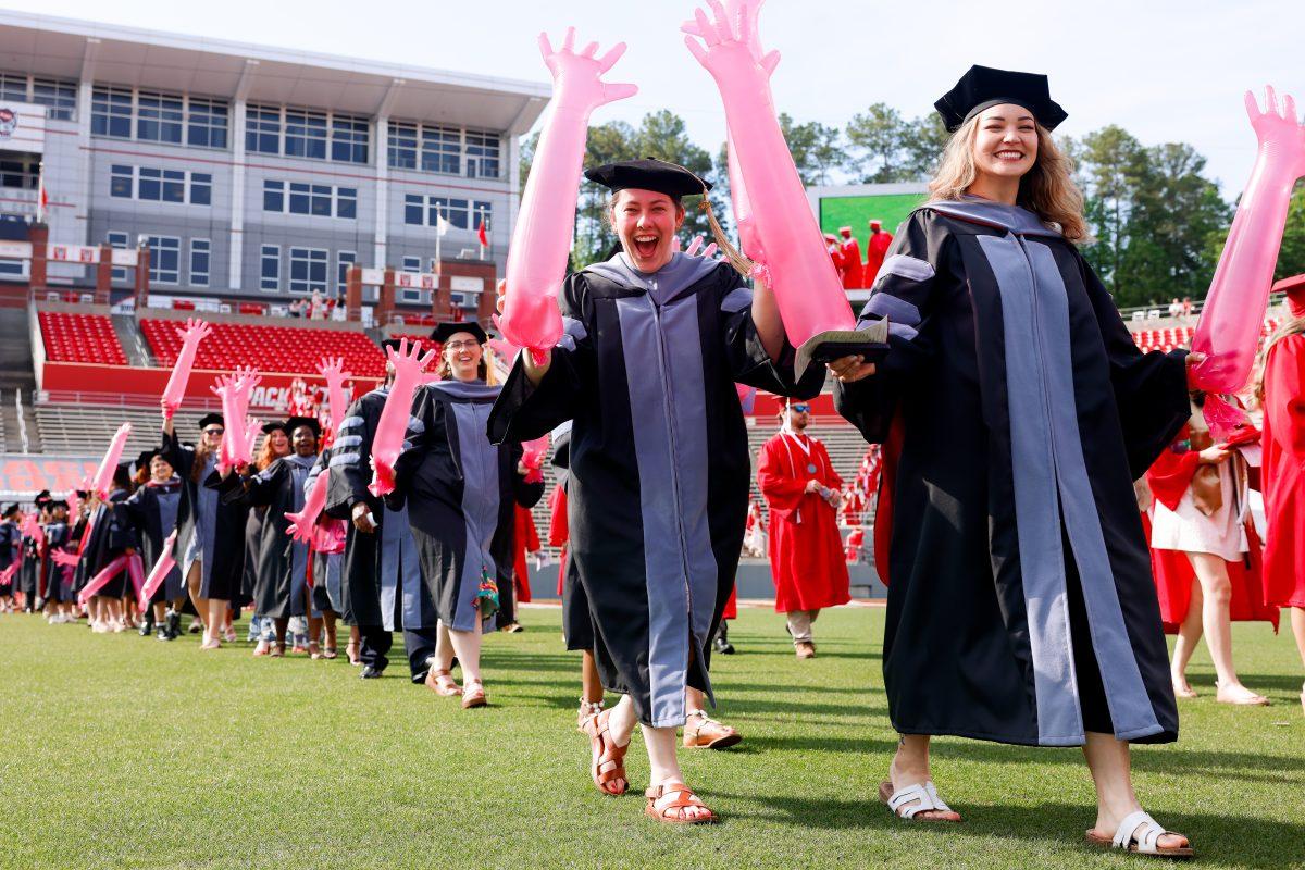 Ellie Cohn, a veterinary school graduate, smiles while holding inlflated veterinary gloves up before the University Commencement ceremony in Carter-Finley Stadium on Saturday, May 3, 2025. Over 5,079 students graduated with Bachelor's degrees at NC States 2025 Spring Commencement Ceremony.