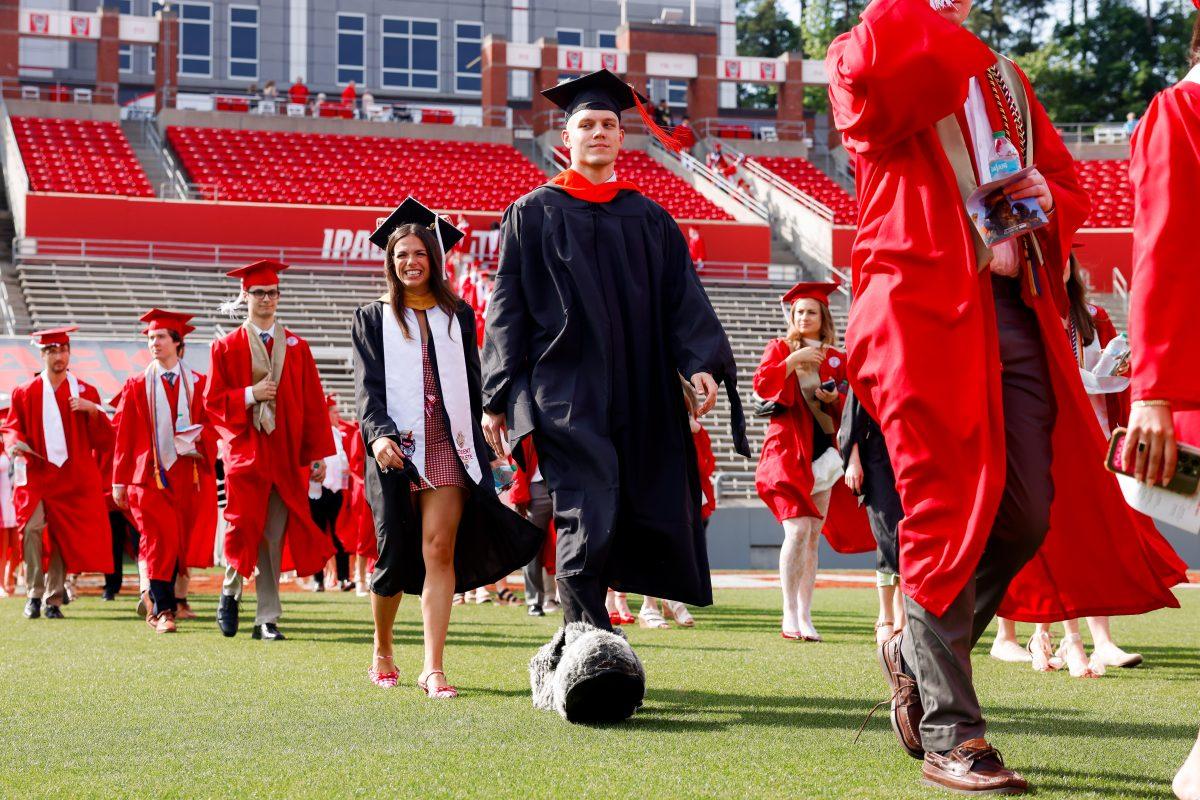 Chase Smith "Mr.Wuf", biomanufacturing masters graduate, and Savana Stone "Mrs.Wuf" smile while walking in to the University Commencement ceremony in Carter-Finley Stadium on Saturday, May 3, 2025. Over 1783 students graduated with Master's degrees at NC States 2025 Spring Commencement Ceremony.