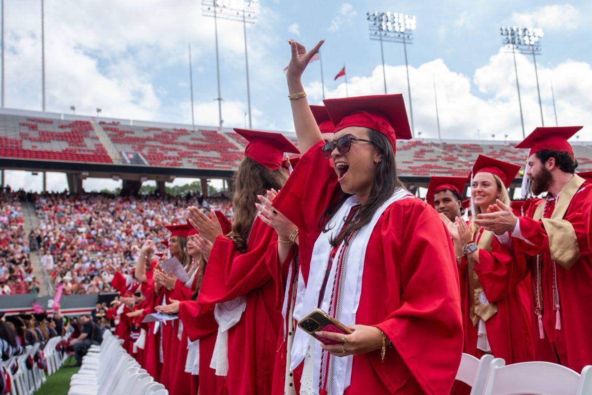 Lauren Ramos, a fourth-year graduating with a degree in textile management, shouts and throws up a "Wolfie" during the University Commencement ceremony in Carter-Finley Stadium on Saturday, May 3, 2025. NC State conferred 7,234 degrees at the ceremony, including 5,079 bachelor&#8217;s, 1,783 master&#8217;s, 306 doctoral, and 66 associate degrees.