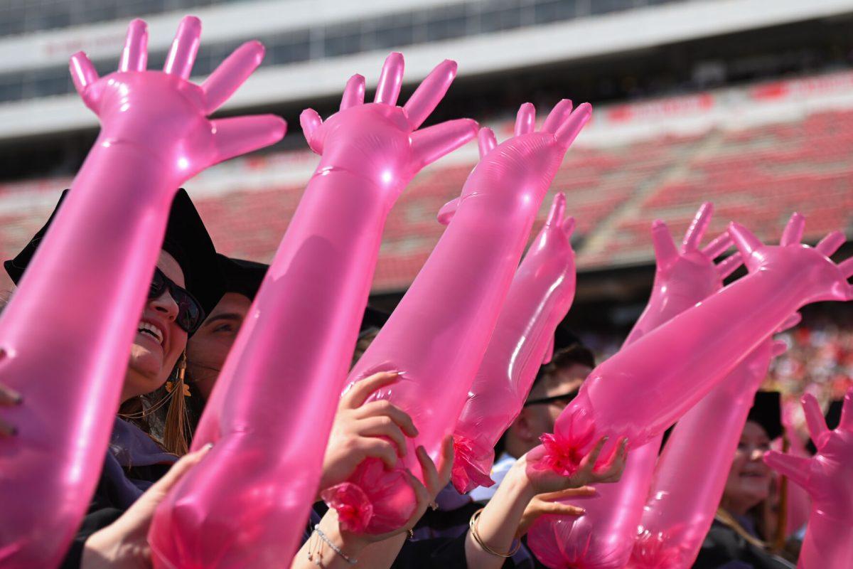 Doctor of veterinary students wave large inflated veterinary gloves while the Ladies in Red perform during the Spring Commencement Ceremony at Carter-Finley Stadium on May 3, 2025. The spring 2025 graduating class included 1,268 first-generation students.