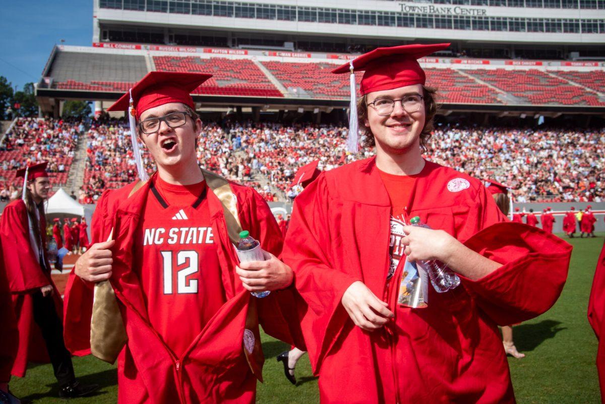 Brian Yngve, a fourth-year graduating with a degree in computer science, and Matthew Roepke, a fourth-year graduating with a degree in civil engineering, rip open their gowns to reveal support for NC State basketball during the University Commencement ceremony in Carter-Finley Stadium on Saturday, May 3, 2025. NC State conferred 7,234 degrees at the ceremony, including 5,079 bachelor&#8217;s, 1,783 master&#8217;s, 306 doctoral, and 66 associate degrees.