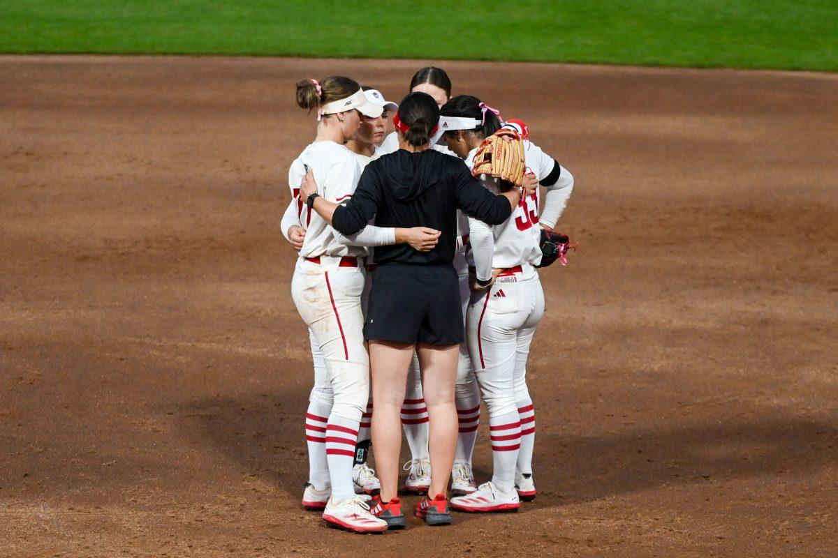 Assistant coach Grayson Radcliffe (center) speaks to members of the softball team during the game against Virginia Tech at Dail Softball Stadium on Friday, April 5, 2025. The Wolfpack lost to the Hokies 10-2.