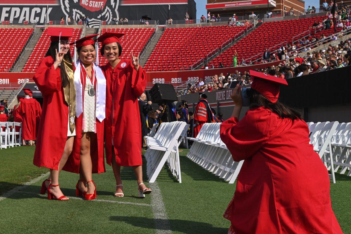 Meredith Bumgarner, graduating with a bachelor's in environmental engineering, Jailyn Russell, graduating with a bachelor's in biological science with a concentration in human biology, and Marilexia Faith Acelajado, graduating with a bachelor's in bioprocessing science, pose for a polaroid picture being taken by Roxy Chaney, graduating with a bachelor's of science in human biology, during the Spring Commencement Ceremony at Carter-Finley Stadium on May 3, 2025. NC State conferred 7,234 degrees in total during the event.